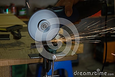 Men cuts a small metal sheet with an electric grinder Stock Photo