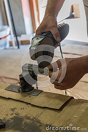 Men cuts a small metal sheet with an electric grinder Stock Photo
