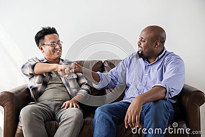 Men fist bumping celebrating on couch Stock Photo