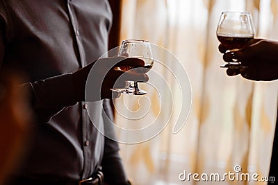Men with a friend standing by the window. hold in the hands of glasses of whiskey. close up Stock Photo