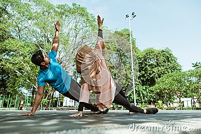 a man and a girl in a veil in gym clothes doing hand exercises together for endurance training Stock Photo