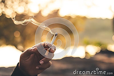 Men hand caught a burning cigarette causing smoke, concept stop smoking Stock Photo