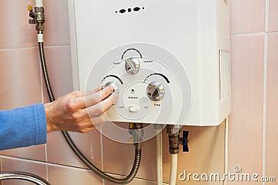 Men hand regulate the power of hot water in Gas water heater. Stock Photo