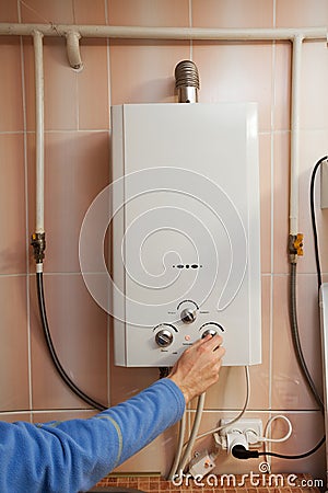 Men hand regulate the temperature of hot water in Gas water heater. Stock Photo