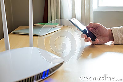 Men hand using smartphone device to connect to wifi network from internet router. Broadband high speed internet network technology Stock Photo