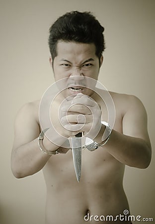 Men in handcuffs holding knife in hand Stock Photo