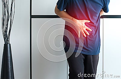 Man having painful stomachache at home,Male suffering from abdominal pain,Hands squeezing belly Stock Photo