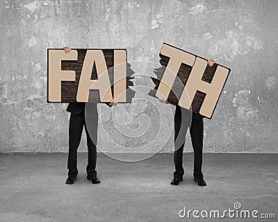 Men holding two cracked FAITH word wooden boards. Stock Photo