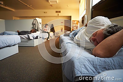 Men Lying On Beds In Homeless Shelter Stock Photo