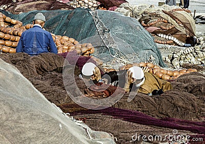 Men lying on fishing nets and discuss Editorial Stock Photo