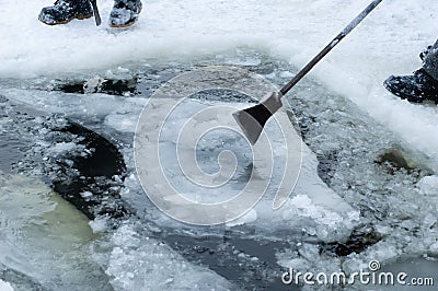Men making ice-hole, cleaning it from ice pieces using crowbar Stock Photo