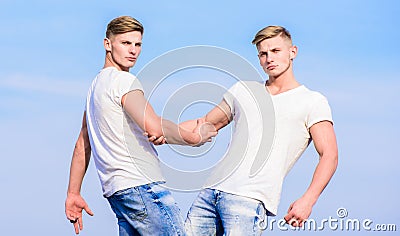 Men muscular twins brothers in white shirts sky background. Brotherhood concept. Benefits and drawbacks of having Stock Photo