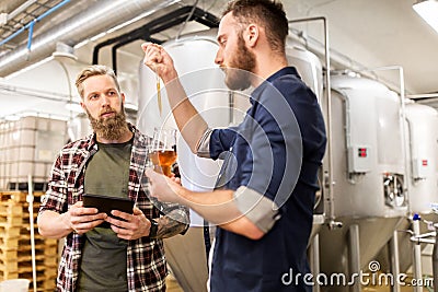 Men with pipette testing craft beer at brewery Stock Photo