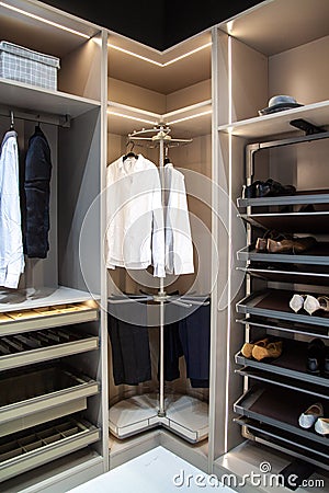 Men's clothes, shirts, pants shoes are kept in the modern convenient wardrobe, clean, organized wardrobe inside view Stock Photo
