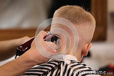 Men`s hairstyling, haircutting, in a barber shop or hair salon. Close-up of man hands grooming kid boy hair in barber shop. Boy Stock Photo