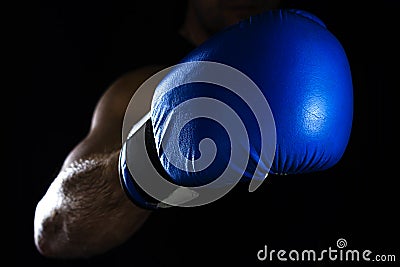 Men`s hand in a blue boxing glove on a black background makes a punch Stock Photo