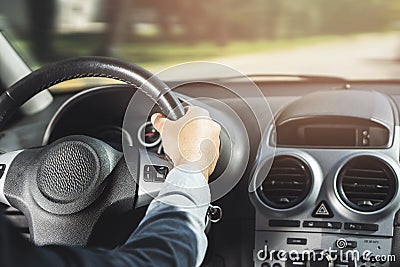 A men`s hand holding black leather finish car whell with silver metallic elements Stock Photo