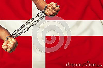 Men`s hands chained in heavy iron chains against the background of the flag of Denmark on a gentle silk with folds in the wind, Stock Photo