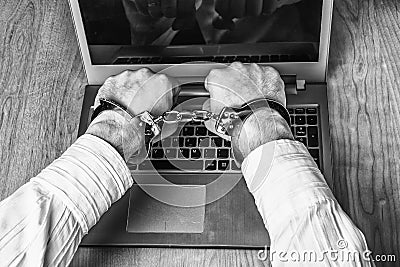 Men`s hands handcuffed on a laptop. Stock Photo