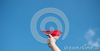 Men`s hands hold a red paper rocket with a bright blue background Stock Photo