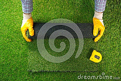 Men`s hands hold a roll of artificial grass. Stock Photo