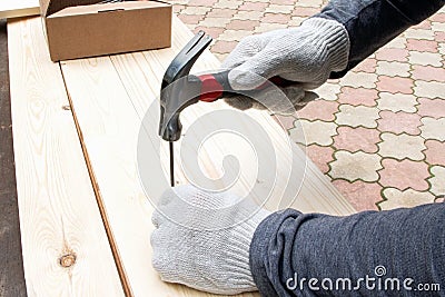 Men`s hands holding a hammer. A hammer striking a nail on a wooden table Stock Photo