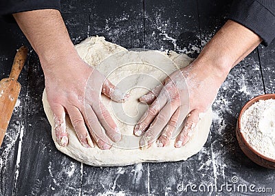 Men`s hands knead a round piece of dough for making pizza Stock Photo