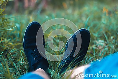 Men`s legs in sneakers in the park on the grass. Stock Photo