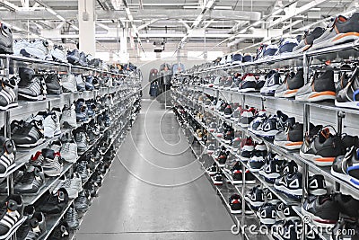 Men`s sports sneakers stand on racks in a clothing and shoe store Editorial Stock Photo