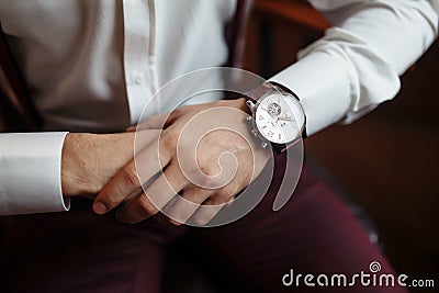 Men`s wrist watch, the man is watching the time. Businessman clock, businessman checking time on his wristwatch. Groom`s Stock Photo