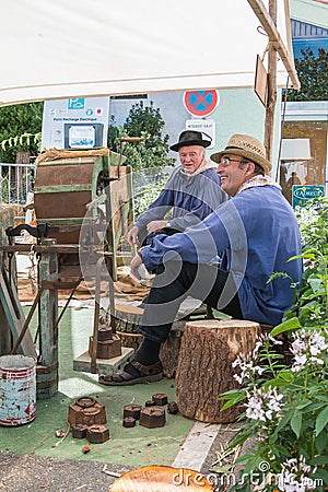 Men sitting next to an ancient machine to thresh grain Editorial Stock Photo