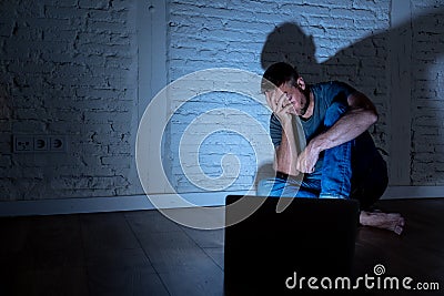 Men suffering Internet cyber bullying sitting alone with computer feeling hopeless Stock Photo