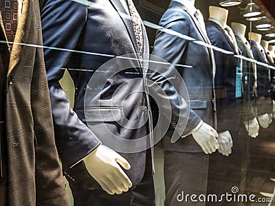 Men Suits, with shirts, ties, pants and blue jackets on display on dummies in front of a tailor store, on a window. Stock Photo