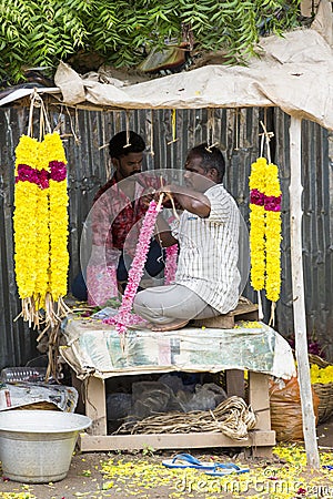 Men threading colourful flower garlands. These flowers are offered to the gods in the temples Editorial Stock Photo
