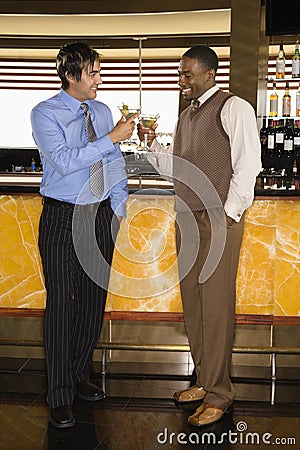 Men toasting at martini bar Stock Photo