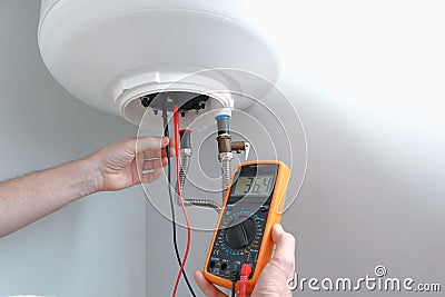 Men using multimeter to test heating element. Appliance engineer using a multimeter carrying out a continuity test on a new Stock Photo