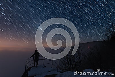 Men is on the viewpoint, under the startrail Stock Photo