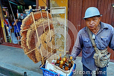 Men wear hat,shirt in blue jean bike parking and bottled honey and honeycomb for sale to tourists Editorial Stock Photo