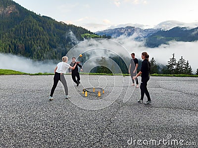 Men and women in their twenties playing a game of spike ball in a mountain parking lot in the Dolomites Stock Photo