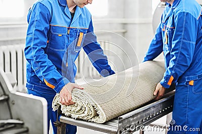 Men workers cleaning get carpet from an automatic washing machine and carry it in the clothes dryer Stock Photo