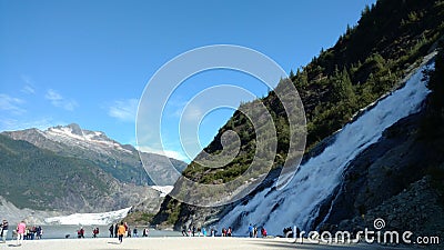 Mendenhall Glacier in Juneau Alaska. Large Glacier sliding into a lake with a waterfall beside it. Very popular tourist stop Editorial Stock Photo