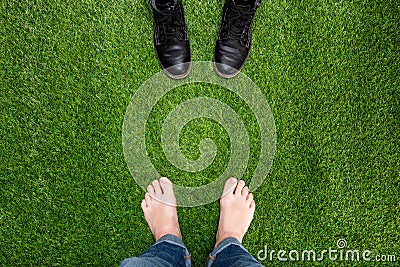 Mens feet resting on green grass standing opposite boots Stock Photo