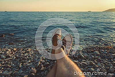 Mens legs in sneakers in background of picturesque sea landscape Summer Beach Relaxing Concept Stock Photo