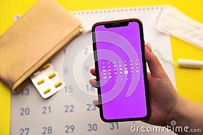 Menstrual cycle concept. Calendar for the month with marks and a mobile application on the smartphone screen Stock Photo