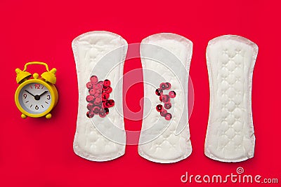 Menstrual pads with bright red glitter and alarm on red background. Woman periods cycle, menstruation frequency Stock Photo