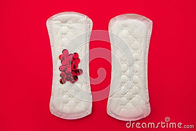 Menstrual pads with bright red glitter on red background. Woman periods cycle, menstruation frequency. Minimalist still Stock Photo