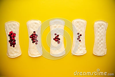 Menstrual pads with bright red glitter on yellow colored background. Woman periods cycle, menstruation frequency Stock Photo