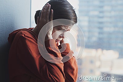 Young sad depressed frustrated autistic woman sitting at home alone suffering from head ache and psychological problems Stock Photo