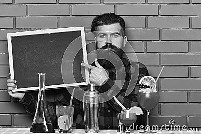 Menu for pub or bar. Barman with beard and serious face holds blank blackboard, chalkboard, Stock Photo