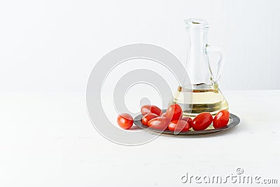 Menu, recipe, mock up, banner. Food background. Glass jug for olive oil, tomatoes on plate, light white background, white wooden Stock Photo